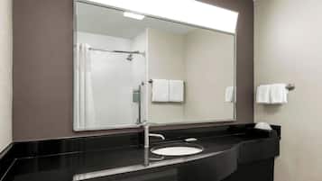Une salle de bain moderne avec un lavabo noir, un grand miroir et une douche visible dans le reflet.
