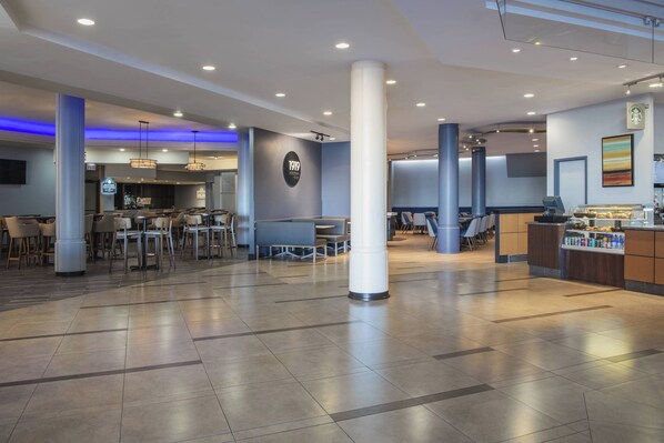 A spacious lobby with a bar area, seating arrangements, and a large pillar.