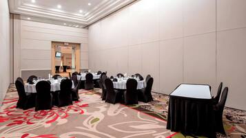 A conference room with round tables, black chairs, and a carpeted floor.