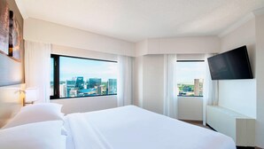 A hotel room with a large bed, a flat-screen TV mounted on the wall, and a city view through large windows. - Delta Hotels by Marriott Regina (Regina)