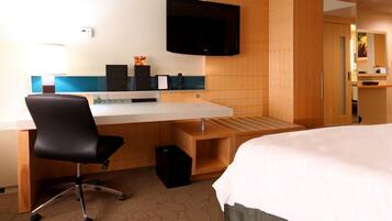 A hotel room with a bed, a desk with a chair, a television, and a wardrobe.