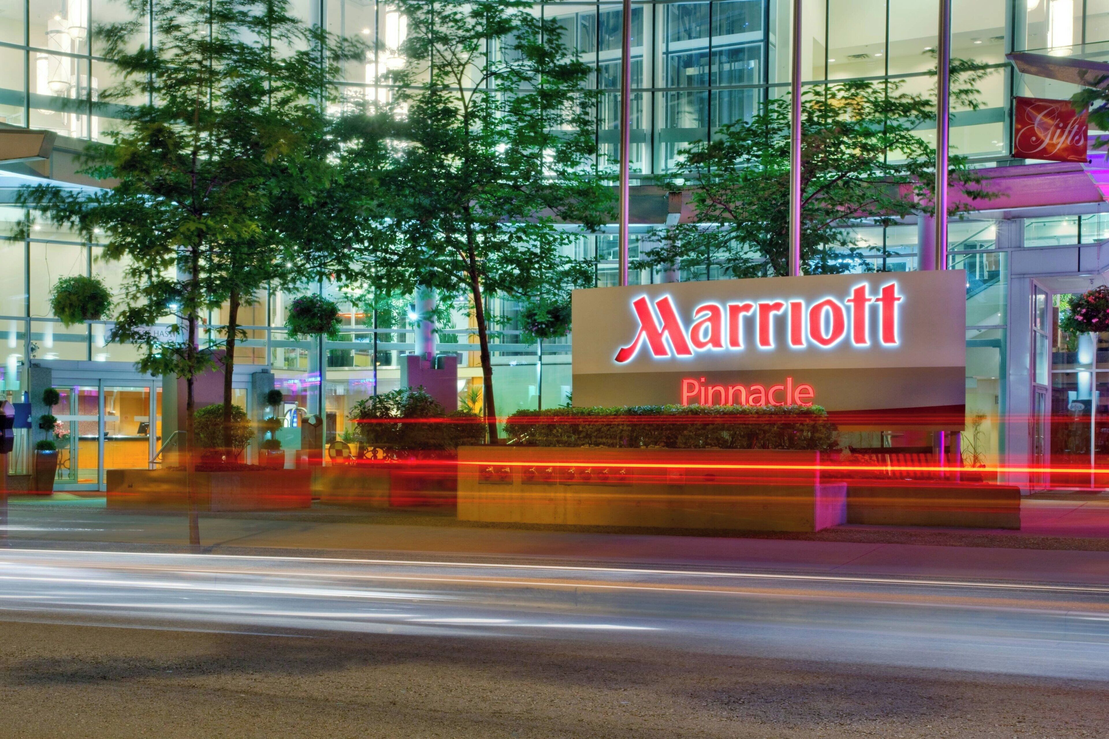 Señal de hotel Marriott Pinnacle con fachada de vidrio moderna y follaje circundante.