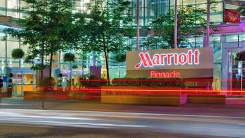 Une enseigne d’hôtel Marriott Pinnacle, avec une façade moderne en verre et une végétation luxuriante tout autour.