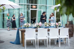 An outdoor dining area with white chairs and tables set up with floral centerpieces. - Vancouver Marriott Pinnacle Downtown (Vancouver)