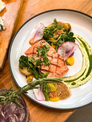 A plate of food with grilled salmon, greens, radish, and a sauce. - Vancouver Marriott Pinnacle Downtown (Vancouver)