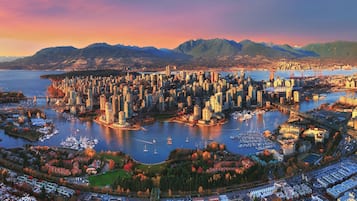 Une vue urbaine comprenant une zone urbaine densément peuplée, une étendue d’eau importante et des montagnes en arrière-plan.