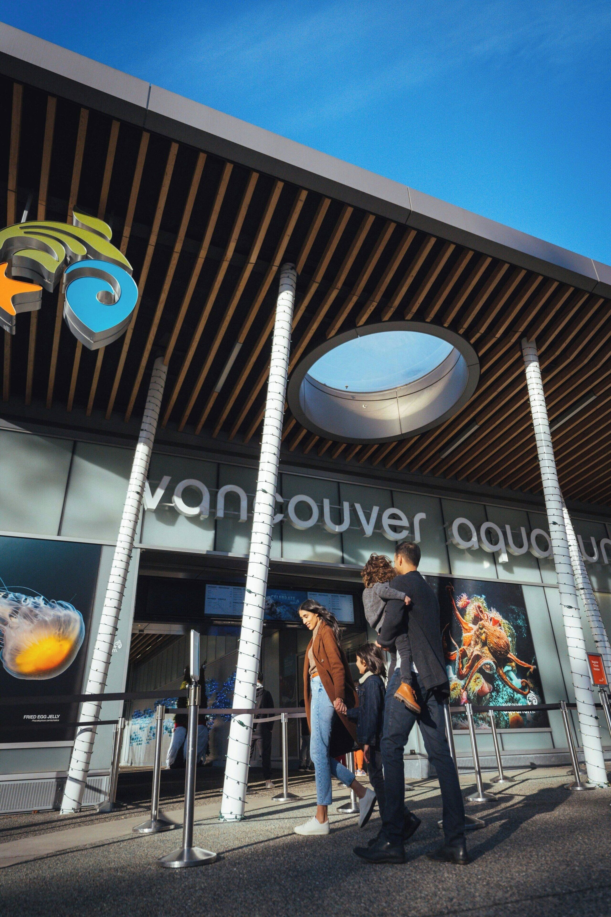 The Vancouver Aquarium entrance with a modern design, including a distinctive logo, a circular skylight, and a wooden slatted roof.