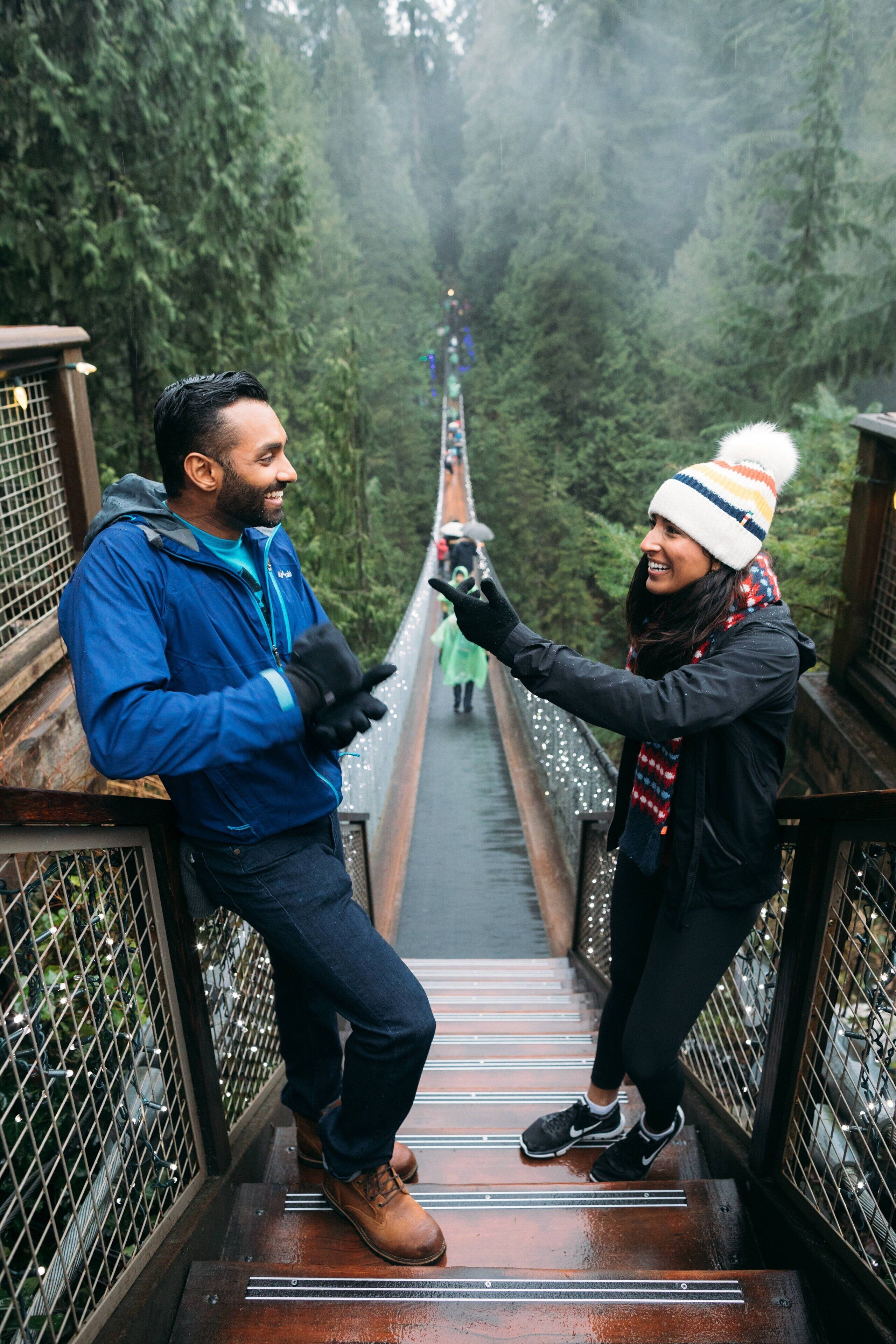 A wooden bridge with metal railings, surrounded by dense forest.