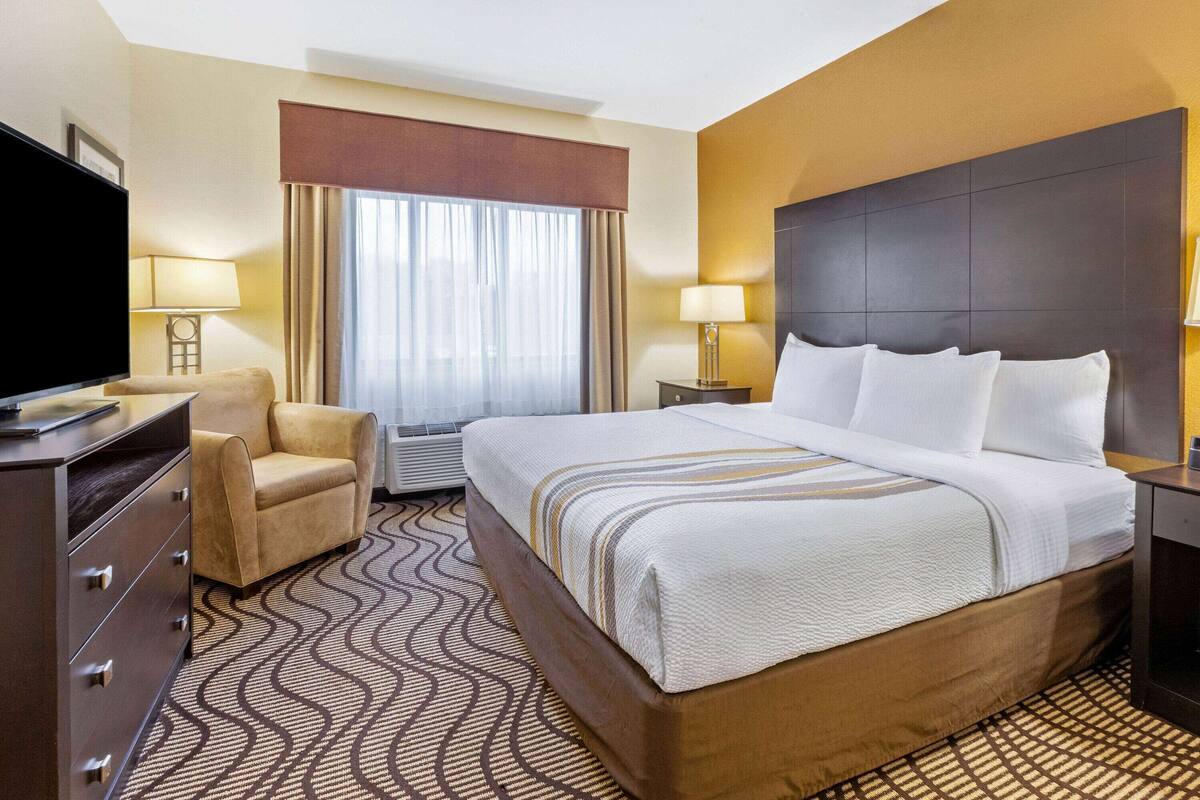 Een hotelkamer met een groot bed, een televisie, een stoel en een bureau.