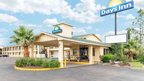 A Days Inn with a central entrance, a parking lot, and surrounding greenery. - Days Inn by Wyndham Snyder (Snyder)