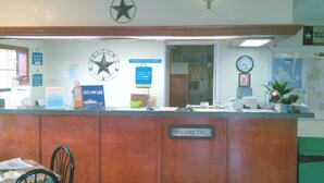A reception desk with a star decoration, a clock, and various informational posters. - Days Inn by Wyndham Snyder (Snyder)
