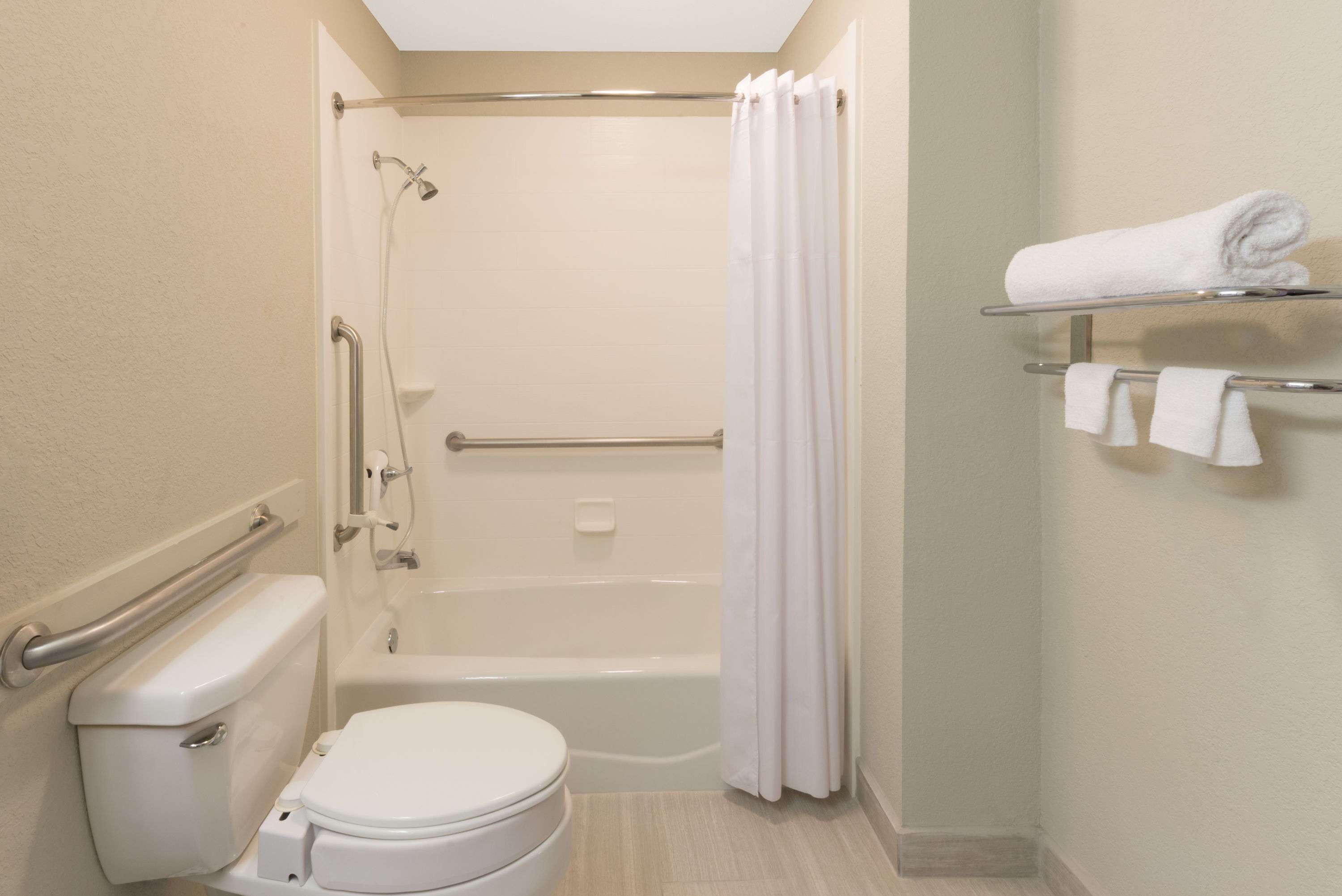 Un baño con inodoro, bañera, ducha y un perchero con toallas.