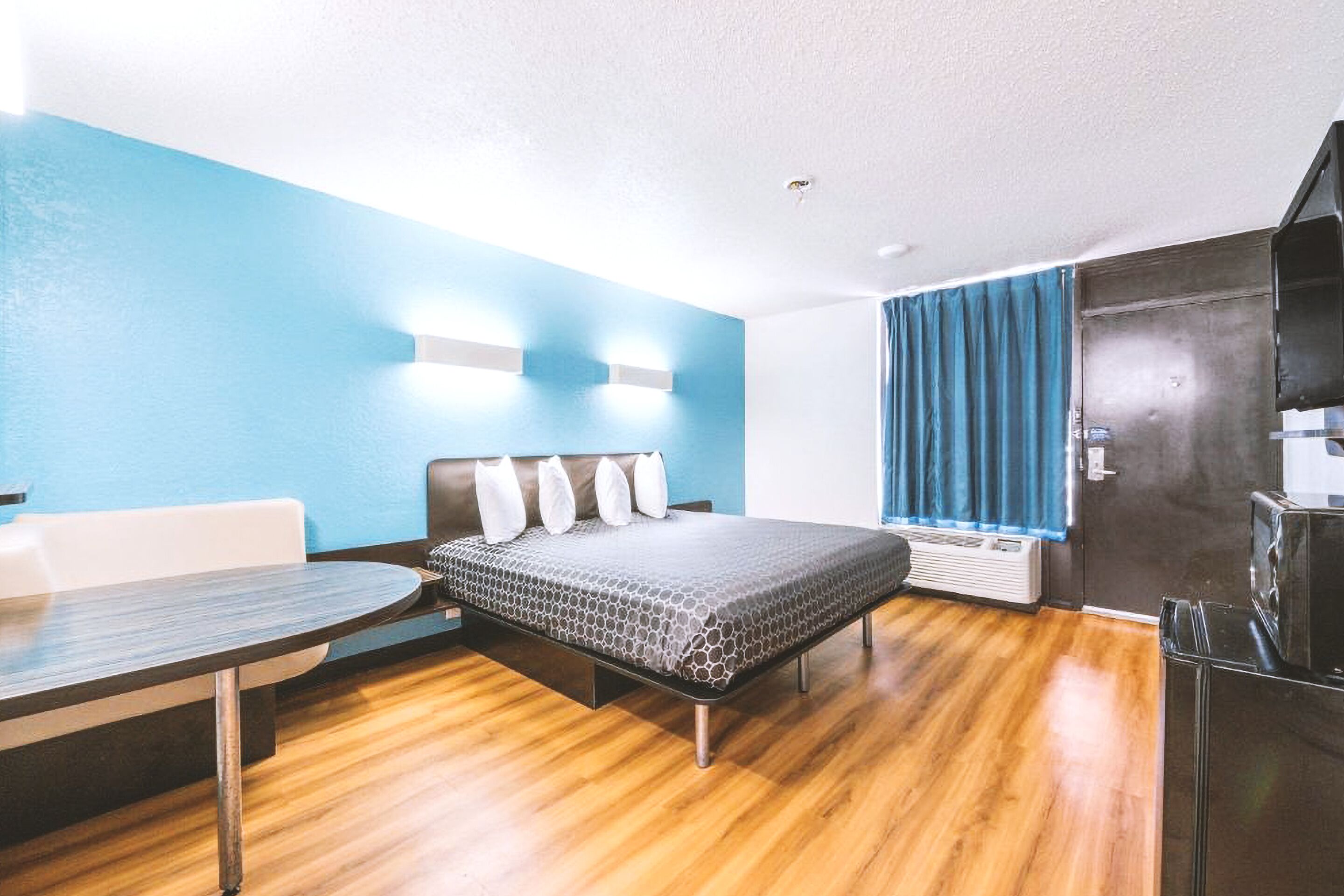 A modern hotel room with a bed, a desk, and a chair.
