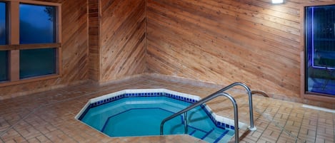Un intérieur en bois avec une piscine, un sol carrelé et un luminaire au plafond.