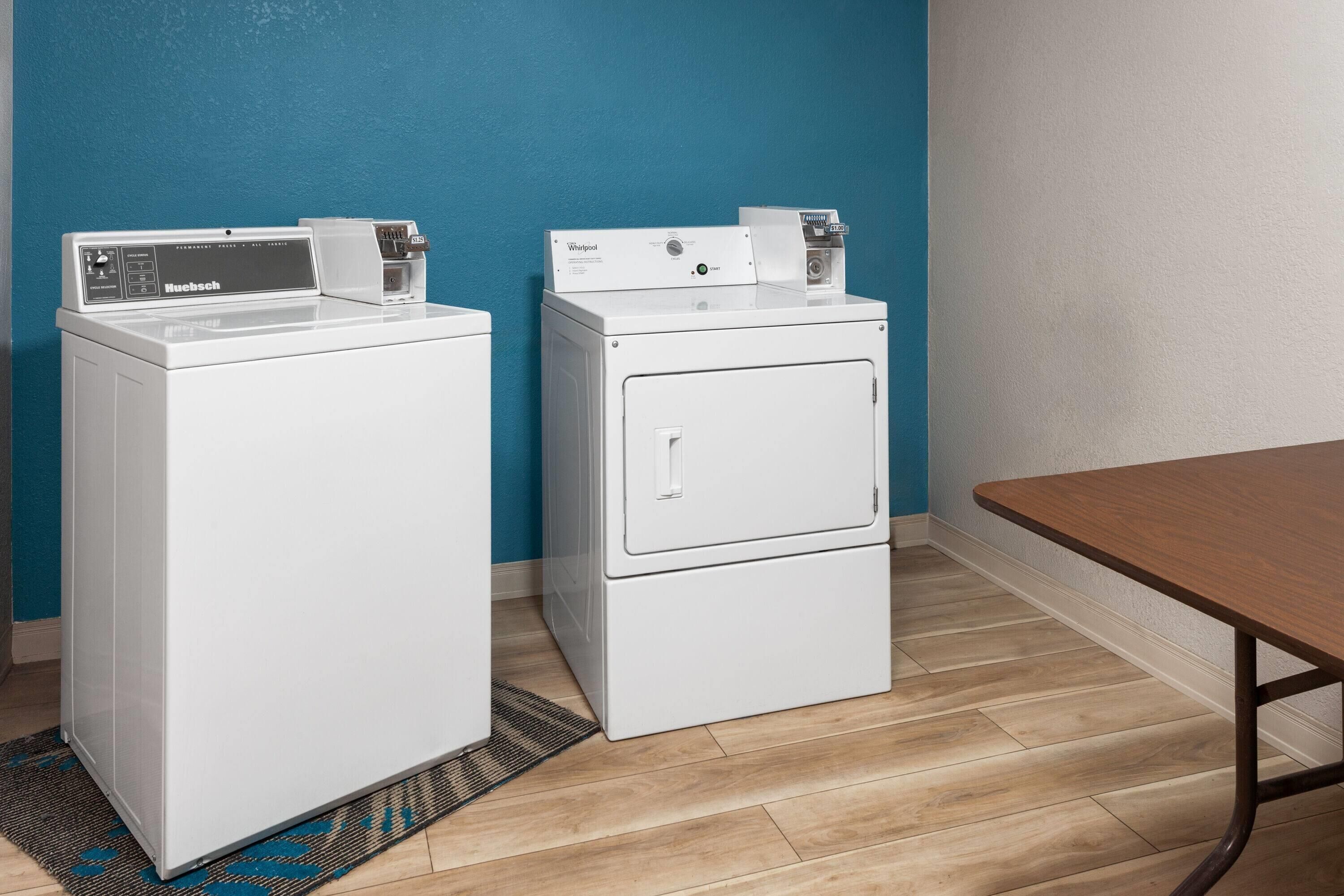 A laundry room with two stacked washing machines, a table, and a blue wall.
