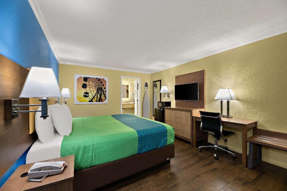 Una habitación de hotel con cama, escritorio, silla y televisor.