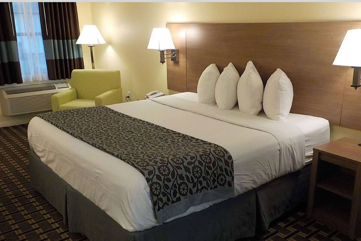 Et hotelværelse med en stor seng, to sengeborde med lamper, en stol og et skrivebord.