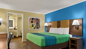 Habitación de hotel con cama, mesitas de noche, un escritorio y una silla. Se observa un cuadro en la pared y una puerta que da a otra habitación.
