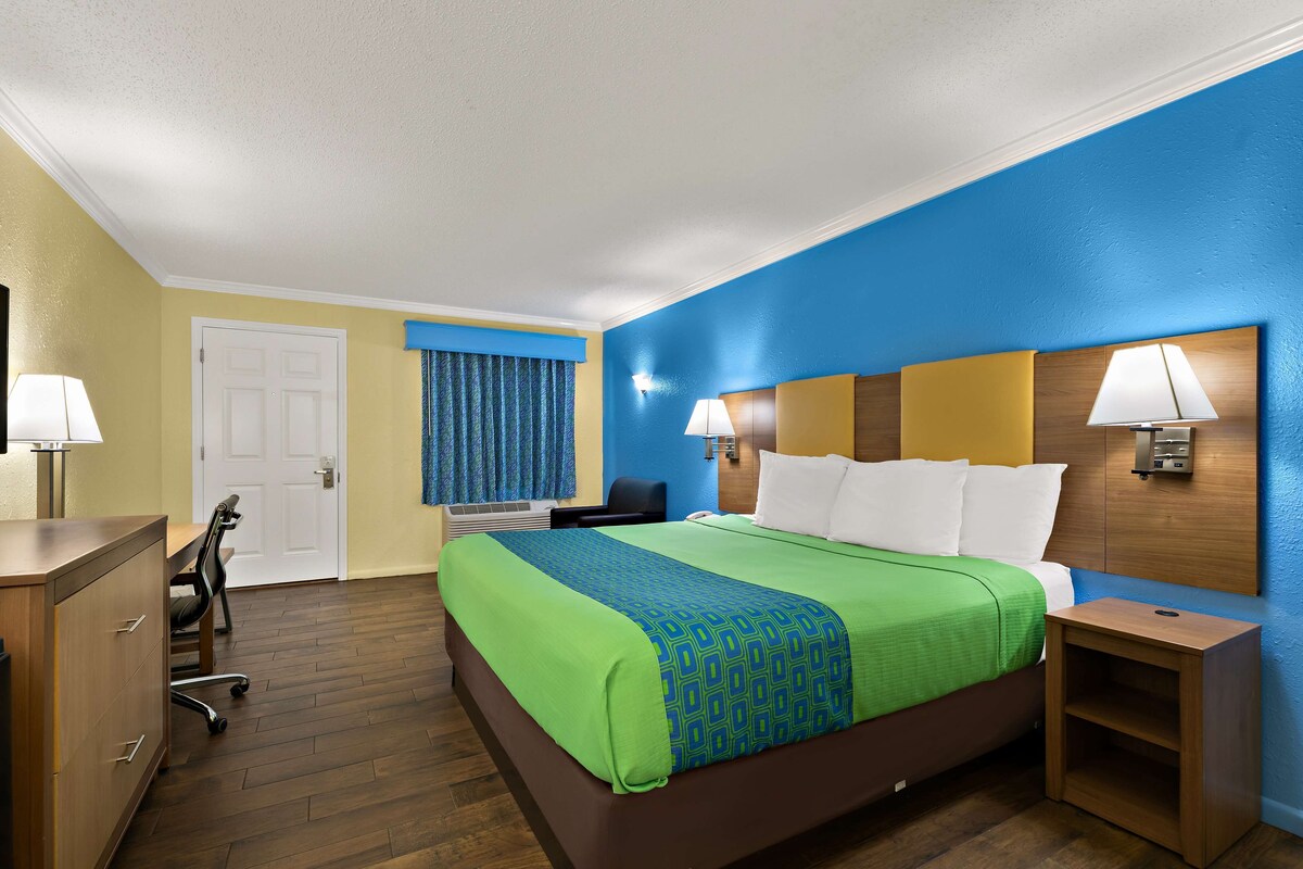 Una habitación de hotel con cama, mesitas de noche, un escritorio y una silla.