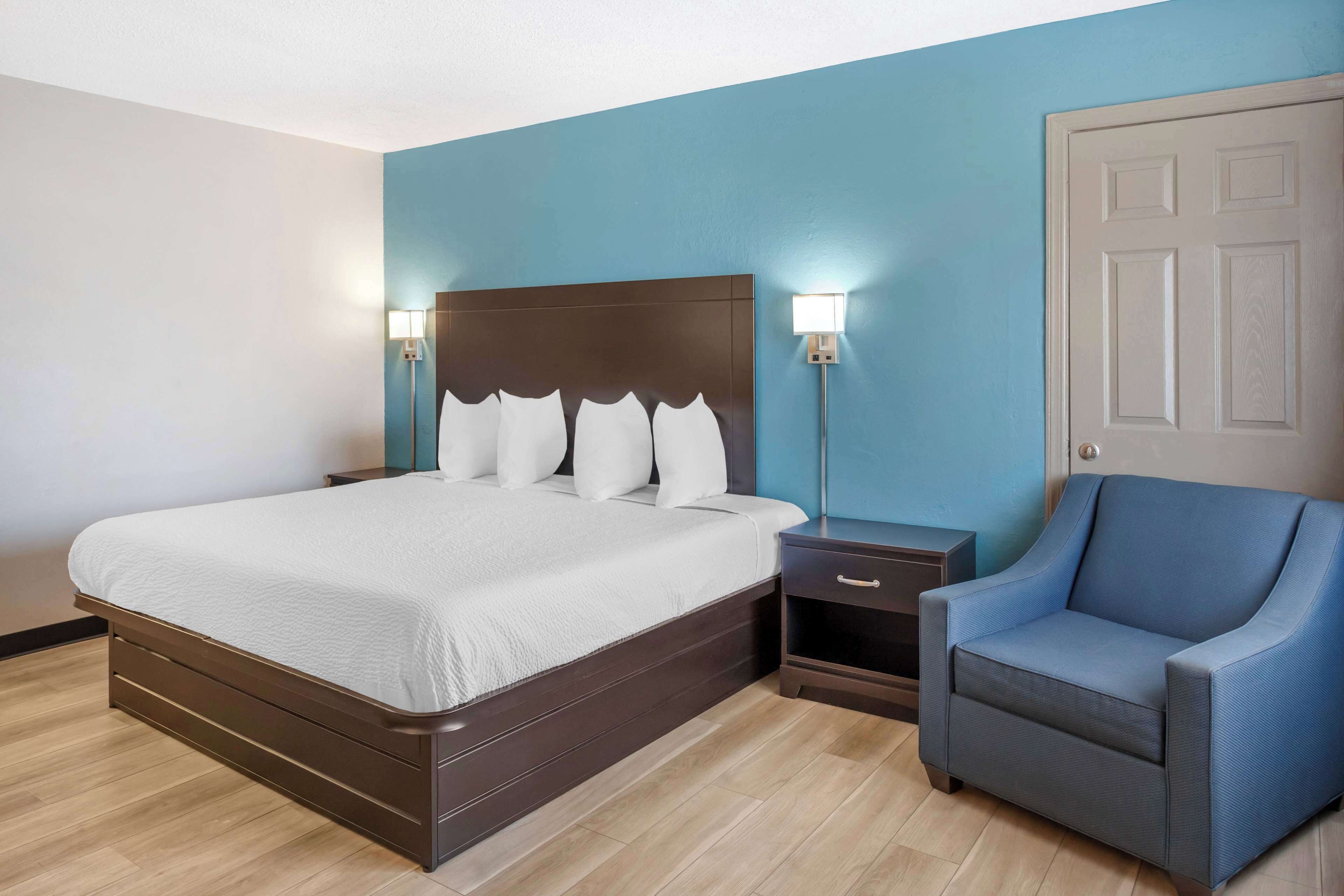 A bedroom with a large bed, bedside tables, a chair, and a door.