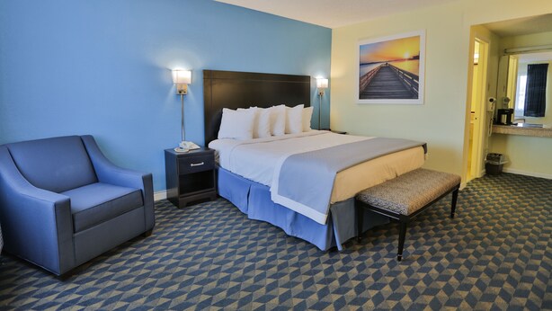 A hotel room with a bed, a chair, a nightstand, and a bench. - Days Inn by Wyndham Wrightstown McGuire AFB/Bordentown (Wrightstown)