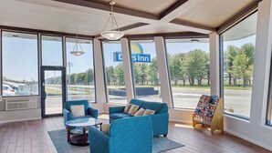 A spacious lobby with large windows, a blue sofa set, a coffee table, and a display stand with brochures. - Days Inn by Wyndham Wrightstown McGuire AFB/Bordentown (Wrightstown)