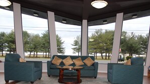 A spacious room with a large window, a teal sofa with multiple cushions, and a round wooden coffee table. - Days Inn by Wyndham Wrightstown McGuire AFB/Bordentown (Wrightstown)