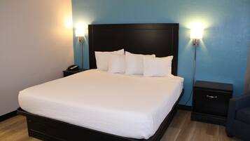 A neatly made bed with a black headboard, two bedside tables with lamps, and a blue wall.