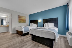 Une chambre d’hôtel avec deux lits, un grand tableau au mur, une table de chevet avec une lampe et une fenêtre avec des rideaux.