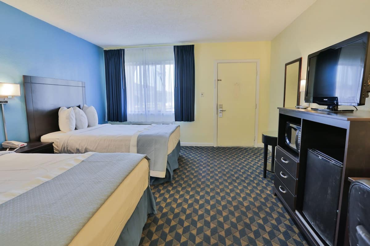 Una habitación de hotel con dos camas, televisión, escritorio y microondas.