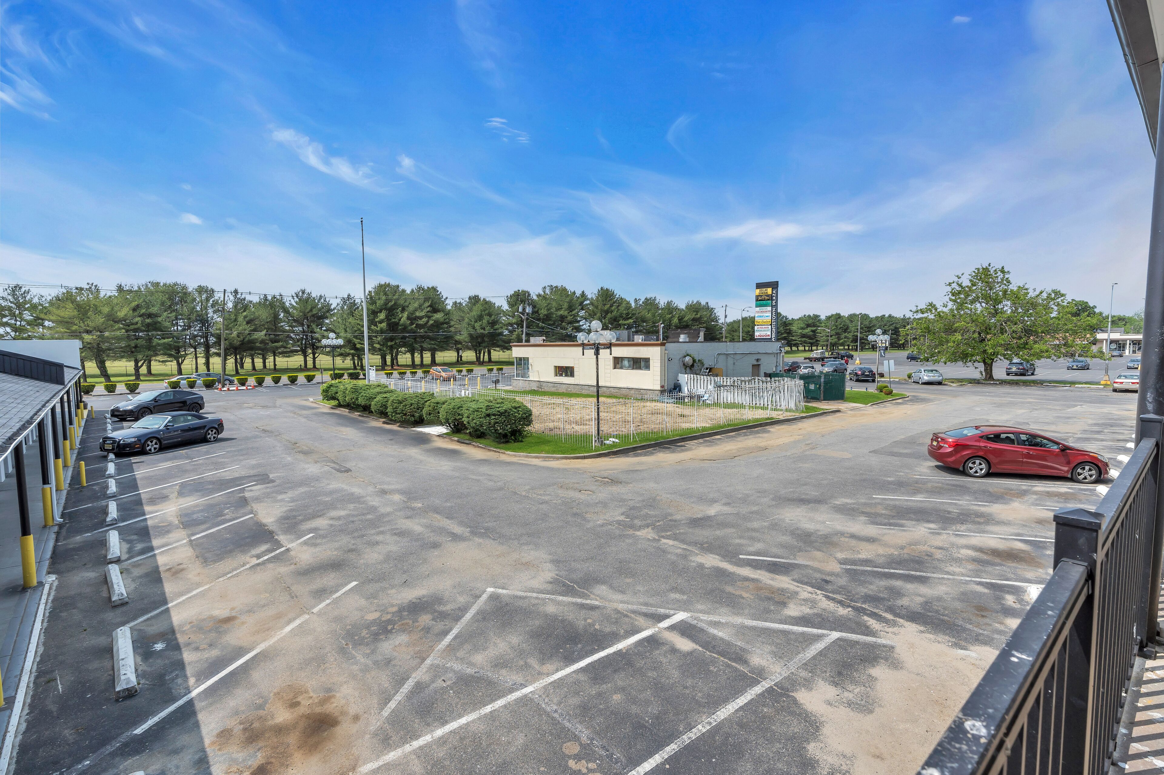 A parking lot with several cars, a small building, and a gas station in the background.