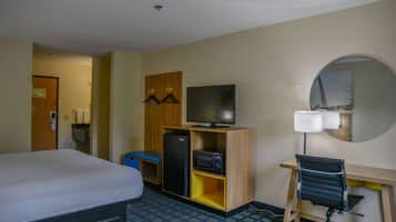 Habitación de hotel con cama, escritorio y silla, televisor, refrigerador y microondas.