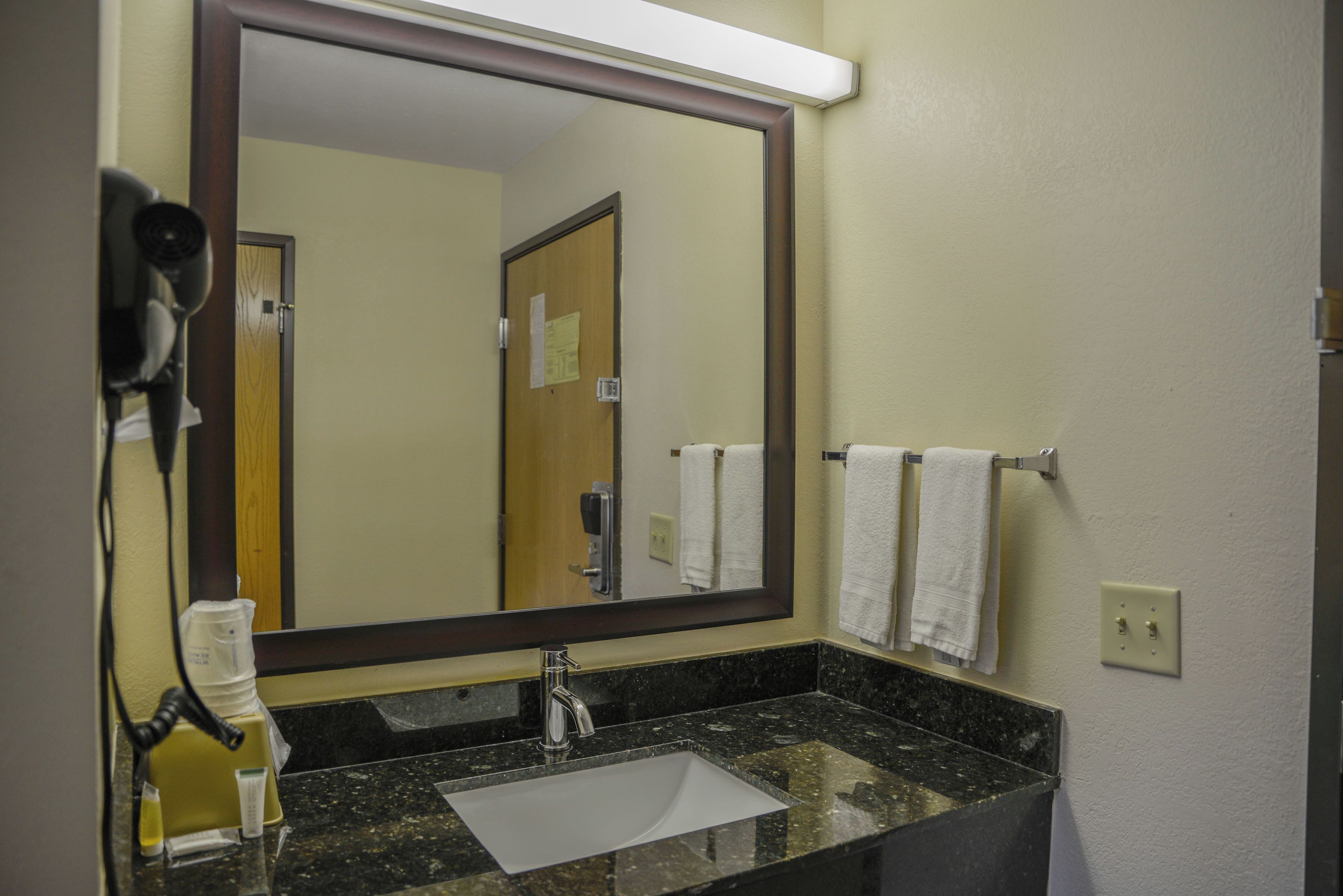 A bathroom with a sink, mirror, and towel rack.