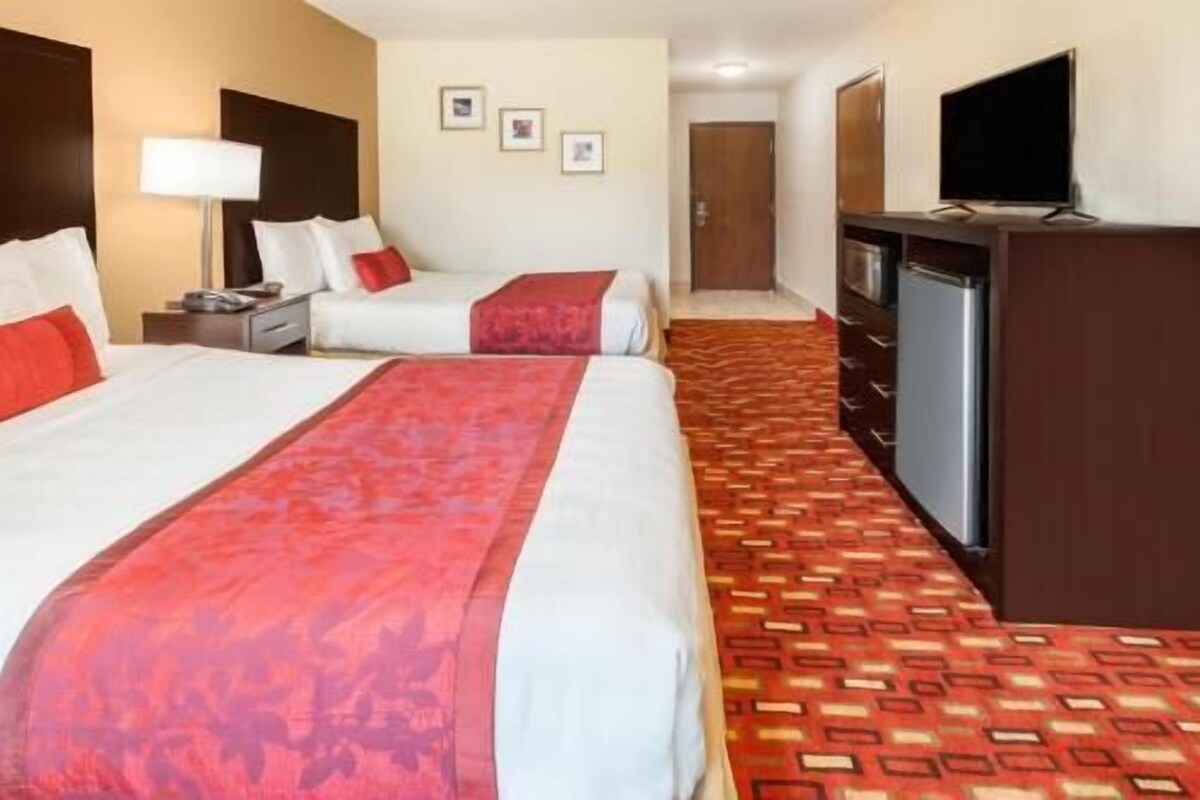 Une chambre d’hôtel avec deux lits, une télévision, un bureau et une armoire.