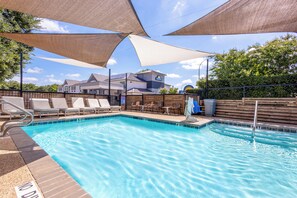 A swimming pool with lounge chairs, a wooden deck, and a covered area with a roof.