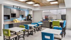 A modern kitchen with built-in appliances, a dining area with colorful chairs, and a large window providing natural light. - Days Inn & Suites by Wyndham Ridgeland (Ridgeland)
