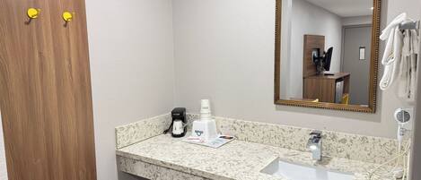 A bathroom with a wooden door, a sink with a marble countertop, a mirror with a gold frame, and a towel rack.