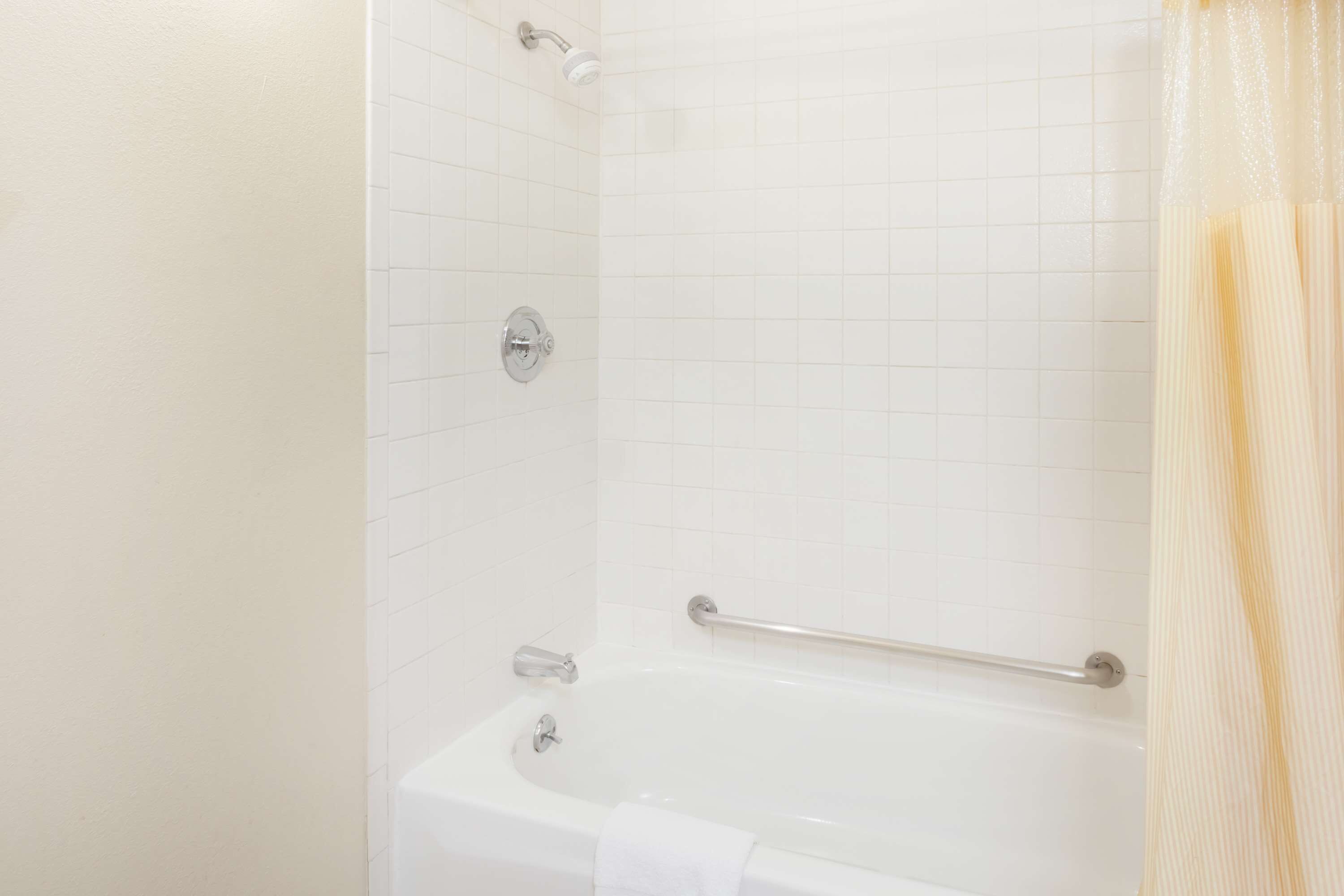 Un baño con una bañera blanca, un cabezal de ducha y un perchero para toallas.