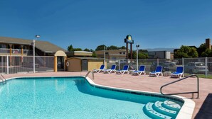 A swimming pool with blue chairs and a lifeguard stand. - Days Inn by Wyndham Ukiah (Ukiah)