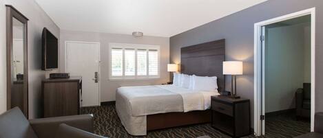 A hotel room with a bed, two bedside tables, a TV, a desk, and a chair.