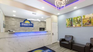 A reception area with a marble counter, a reception desk, and a sign that reads "Days Inn by Wyndham". There are two leather armchairs and a door in the background. - Days Inn by Wyndham Ukiah (Ukiah)