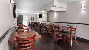 A restaurant interior with wooden tables and chairs, recessed lighting, and a modern ceiling design. - Days Inn by Wyndham Wildwood I-75 (Wildwood)