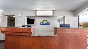 A reception desk with a Days Inn logo, a clock, and a flat-screen TV. - Days Inn by Wyndham Wildwood I-75 (Wildwood)