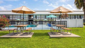 A hotel with a swimming pool, picnic tables, and umbrellas. - Days Inn by Wyndham Wildwood I-75 (Wildwood)