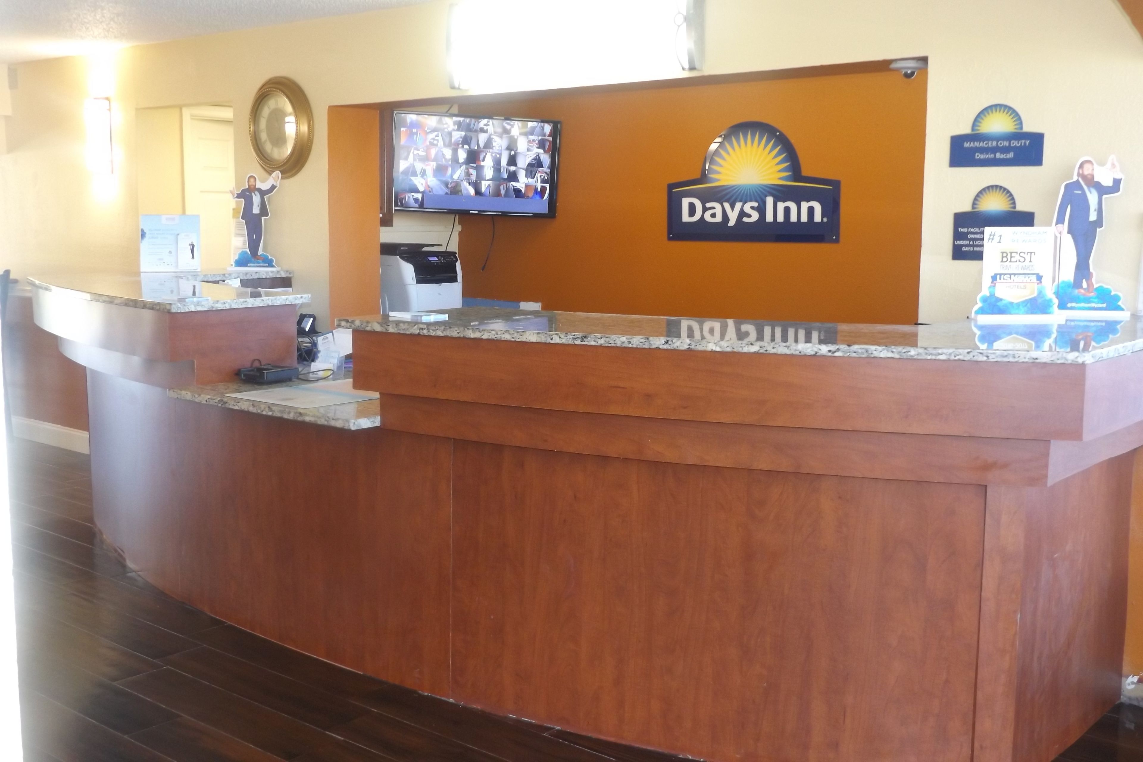 A reception desk with a Days Inn logo, a television mounted above it, and a 'Manager on Duty' sign.