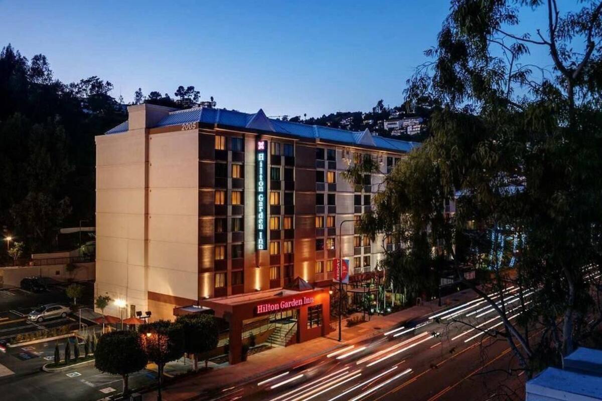 A multi-story hotel with a prominent entrance, a parking area, and a view of the surrounding area.