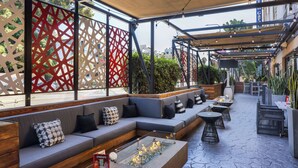 An outdoor seating area with cushioned benches, a fire feature, and a stone-tiled floor. - Hilton Garden Inn Los Angeles/Hollywood (Los Angeles)
