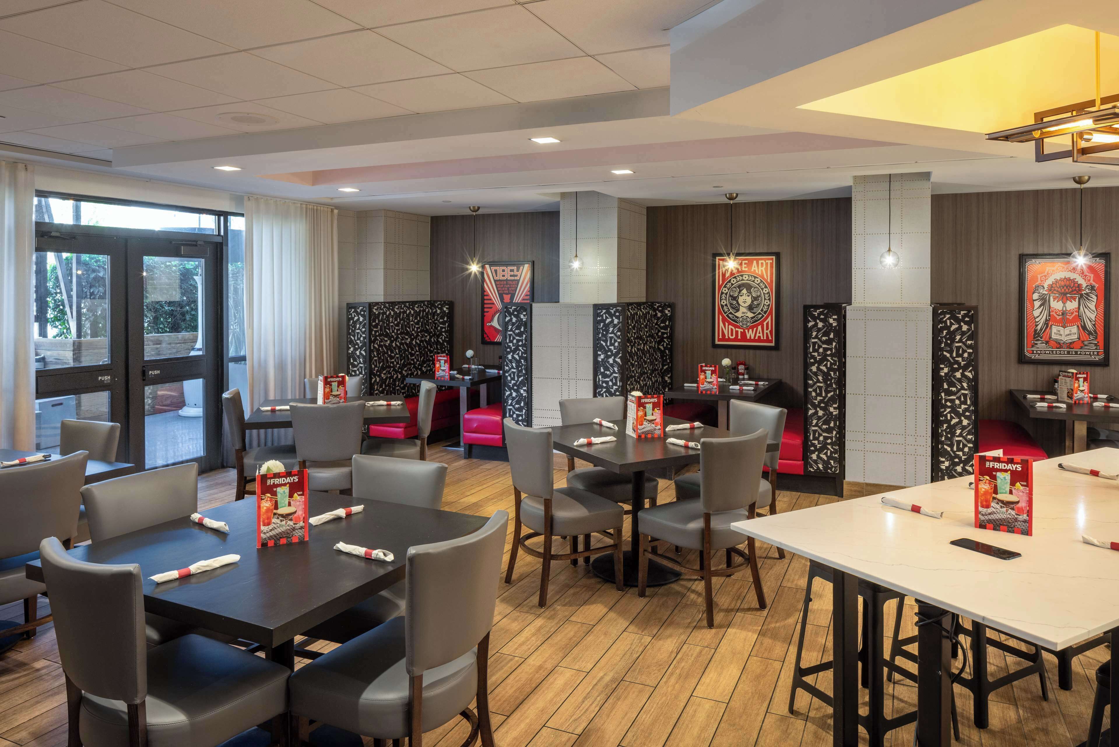 A restaurant with tables and chairs, a counter, and a view of the outside.