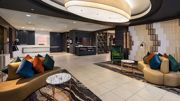 A modern lobby with a reception desk, sofas, a bar area, and a seating area with a patterned rug. - Hilton Garden Inn Los Angeles/Hollywood (Los Angeles)