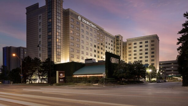 Un hôtel au design moderne, avec une enseigne DoubleTree by Hilton bien visible, une entrée bien éclairée et un parking situé à l’arrière.